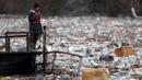 Pekerja perusahaan utilitas mendorong limbah ke tepi Sungai Lim dekat Priboj, Serbia, 30 Januari 2023. Botol plastik, papan kayu, tong berkarat, dan sampah lainnya dari tempat pembuangan sampah tepi sungai yang tidak diatur dengan baik terakumulasi selama air pasang. (AP Photo/Armin Durgut)