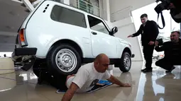 Ekspresi Norik Yajian menahan sakit ketika tubuhnya dilindas sebuah mobil di Tbilisi, Georgia, Selasa (16/2). Atraksi ini nekat dilakukan Norik untuk memecahkan rekor Guinness. (REUTERS/David Mdzinarishvili)