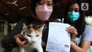 Pemilik menunjukkan kucing dan surat saat mengikuti vaksinasi rabies di halaman Kantor RPTRA Hati Suci, Kampung Bali, Jakarta, Selasa (25/1/2022). Sudin KPKP Kota Administrasi Jakarta Pusat Kecamatan Tanah Abang menyediakan 100 dosis vaksin rabies dalam kegiatan tersebut. (merdeka.com/Imam Buhori)