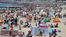 Orang-orang mencoba untuk melakukan jaga jarak ketika berjemur menikmati cuaca panas di pantai pada hari libur umum di Bournemouth, Senin (25/5/2020). Inggris mulai melonggarkan beberapa pembatasan yang diberlakukan untuk mengendalikan penyebaran virus corona Covid-19. (Andrew Matthews / PA via AP)