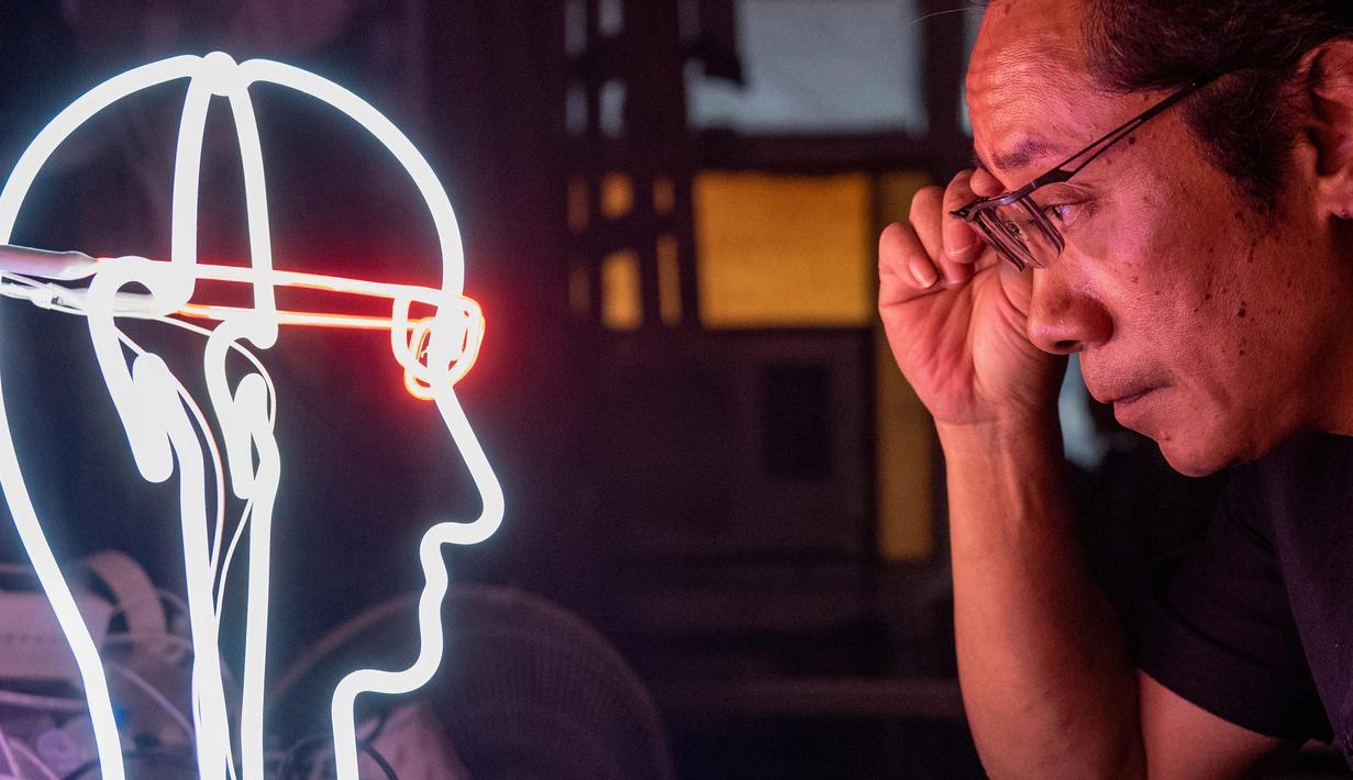 Wu Chi-kai melihat salah satu karyanya selama wawancara dengan AFP di Hong Kong (16/4). Wu Chi-kai merupakan salah satu pengrajin neon sign yang tersisa dari jenisnya di Hong Kong. (AFP Photo/Philip Fong)