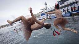 Sejumlah peserta berkostum khas hari Natal melompat ke dalam air dalam ajang Copa Nadal yang berlangsung di Barcelona's Port Vell, Barcelona, Kamis (25/12/2025) waktu setempat. Acara tersebut diikuti lebih dari 450 peserta. (AFP/Josep Lago)