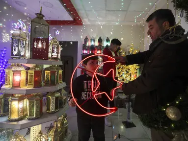 Warga Palestina berbelanja lentera tradisional "fanous" di Hebron di Tepi Barat yang diduduki pada 27 Maret 2022. Fanous merupakan lentera untuk dekorasi yang digunakan merayakan awal bulan suci Ramadan. (HAZEM BADER / AFP)