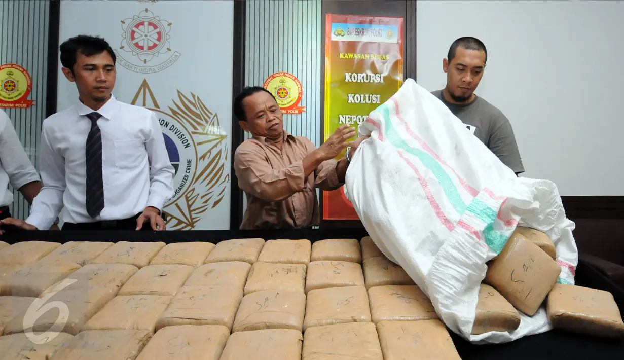 Petugas Dir IV Narkoba Mabes Polri membongkar karung berisi puluhan pak ganja saat rilis di Jakarta, Selasa (24/5/2016). Petugas menahan enam orang tersangka dengan barang bukti narkoba jenis ganja seberat satu ton. (Liputan6.com/Helmi Fithriansyah)
