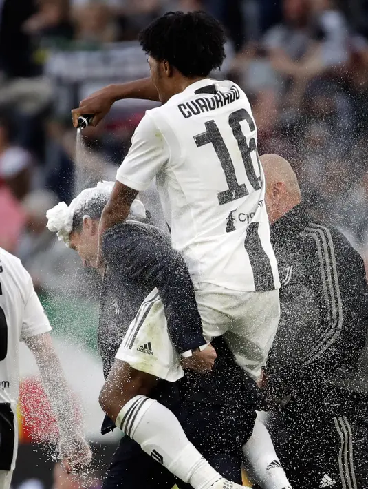 Pemain Juventus Juan Cuadrado menyemprotkan busa pada pelatih Massimiliano Allegri pada akhir pertandingan saat menghadapi Fiorentina dalam Serie A Liga Italia di Stadion Allianz, Turin, Italia, Sabtu (20/4). Juventus menjuarai Serie A Liga Italia 2018/2019. (AP Photo/Luca Bruno)