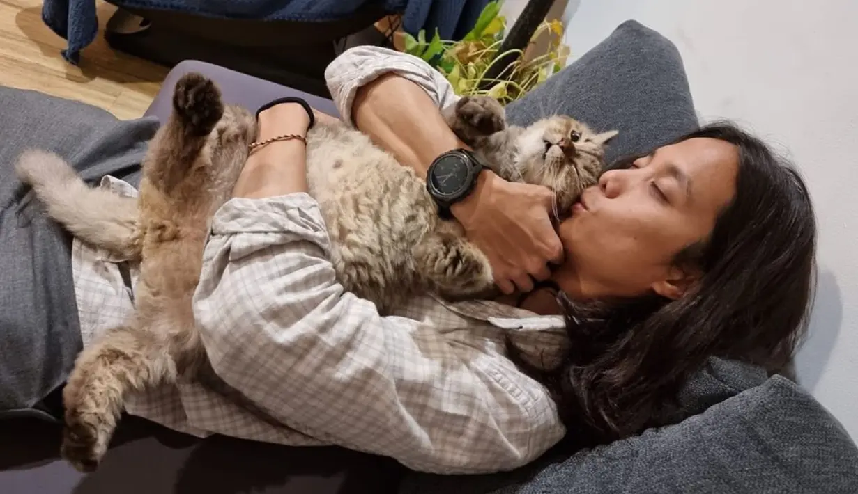 Dikta mencium gemas Jimbon saat bersantai di sofa. Kucing peliharaan Dikta merupakan kucing jenis persia. (Instagram/@dikta)