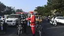 Presiden Angel Foundation dan pekerja sosial, Rufas Christian, berpakaian Sinterklas saat membagikan masker di persimpangan lalu lintas di Ahmedabad, India, Kamis (17/12/2020). Aksi itu sebagai bagian dari kampanye kesadaran melawan penyebaran virus corona COVID-19. (SAM PANTHAKY/AFP)