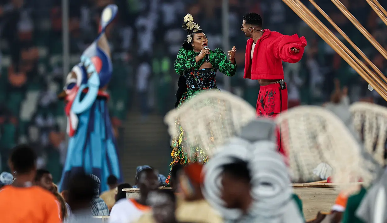 Penampilan penyanyi Nigeria, Yemi Alade (kiri) dan penyanyi Mesir, Mohamed Ramadan saat pesta pembukaan Piala Afrika 2023 yang berlangsung di Stadion Alassane Ouattara Olympic, Abidjan, Pantai Gading, Minggu (14/01/2024) dini hari WIB. (AFP/Franck Fife)