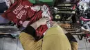Siti Zahro (44) menyelesaikan pembuatan celemek berbahan tas bansos Covid-19 di industri jahit rumahan KG-Lupe Fashion, Salemba, Jakarta, Senin (16/11/2020). Siti berinovasi membuat celemek berbahan tas bansos Covid-19 yang didapat dari pemerintah selama PSBB. (merdeka.com/Iqbal S. Nugroho)