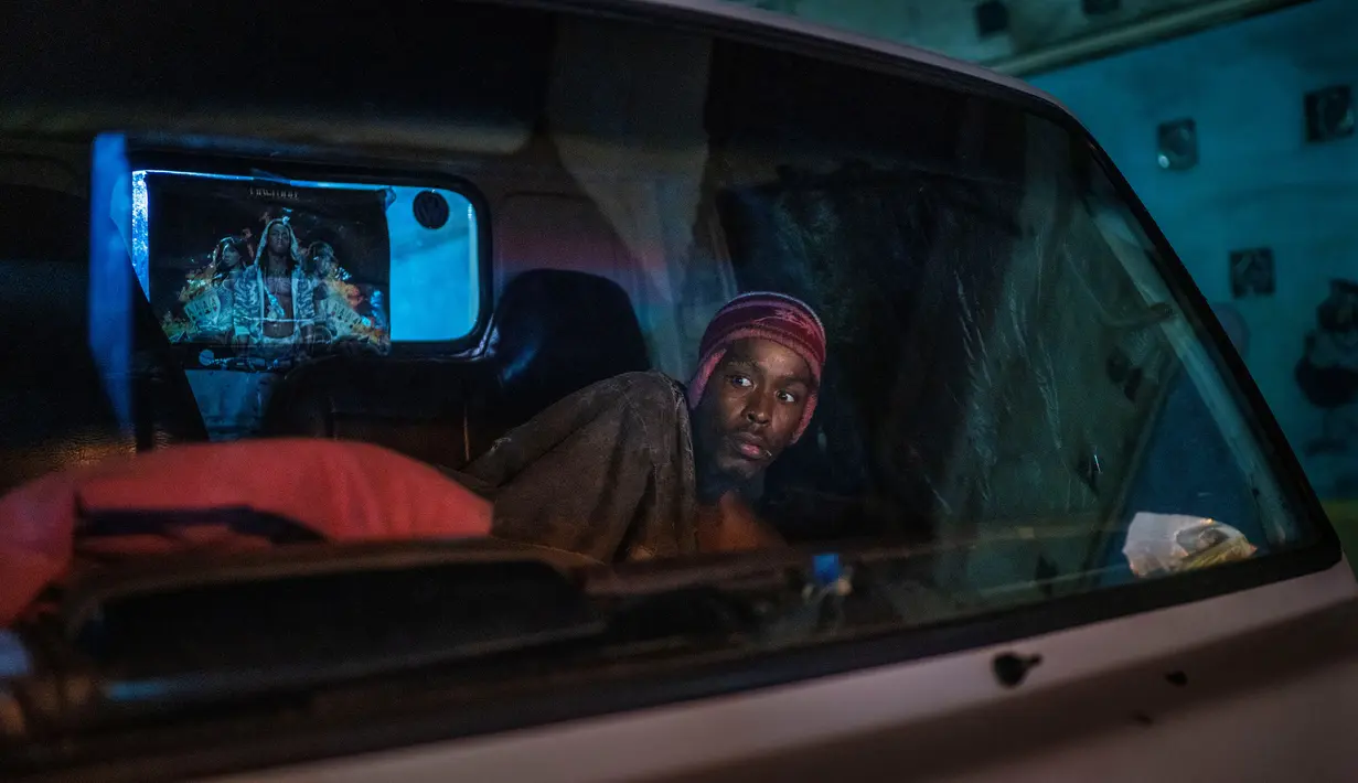 Seorang pria berada di mobil saat petugas berpatroli di pusat kota Johannesburg, Afrika Selatan, Jumat Jumat (27/3/2020). Polisi dan tentara mulai berpatroli beberapa saat setelah Afrika Selatan melakukan Lockdown 21 Hari dalam upaya untuk mengurangi penyebaran Covid-19. (AP Photo/Jerome Delay)