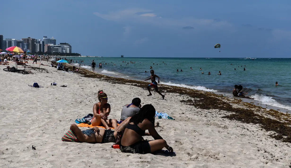 Orang-orang menghabiskan waktu di Miami Beach, Florida, Rabu (10/6/2020). Pantai Miami dibuka hari ini untuk pertama kalinya setelah hampir tiga bulan ditutup guna menekan jumlah penyebaran corona Covid-19. (CHANDAN KHANNA / AFP)