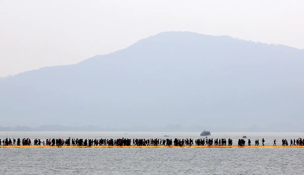 Wisatawan berjalan di atas instalasi "The Floating Piers" di Danau Iseo, Italia, (24/6). Seni instalasi yang mengambang di atas Danau Iseo menghubungkan Desa Sulzano ke pulau kecil Monte Isola yang berada di tengah danau. (REUTERS/Stefano Rellandini)
