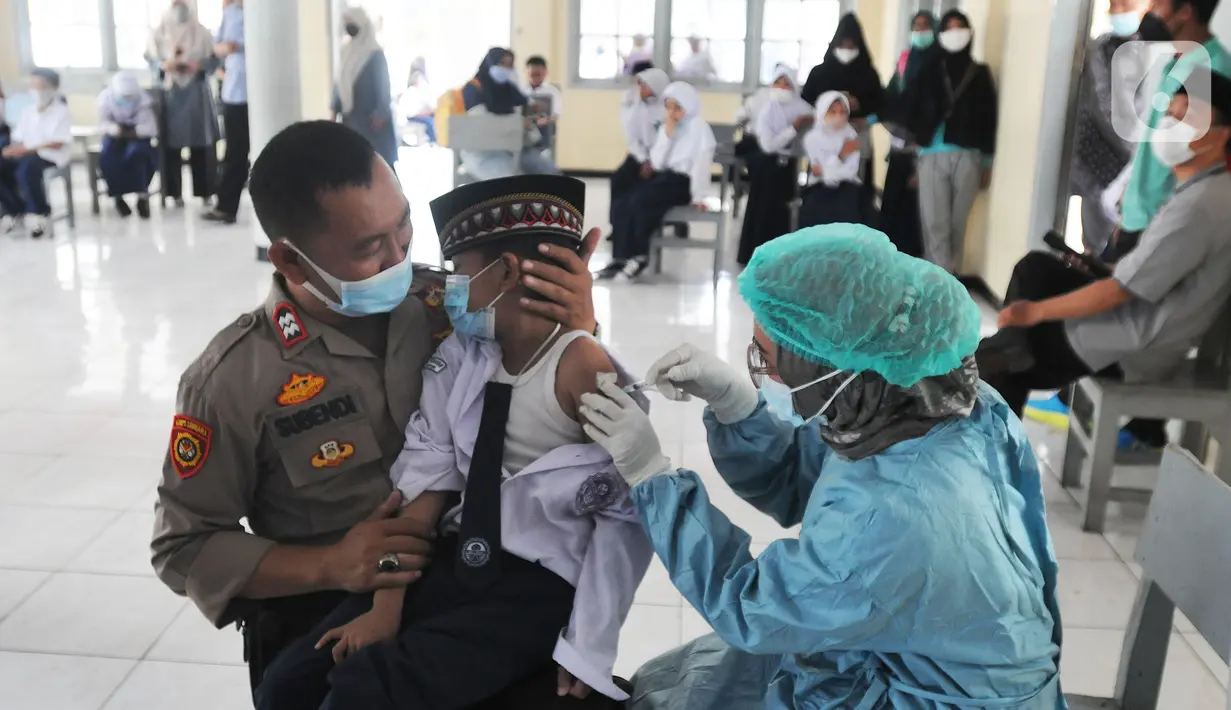 Anggota Polsek Cinere mendampingi murid kelas II saat vaksinasi covid-19 di SDI Al Hidayah, Depok, Selasa (25/1/2022). Mengantisipasi meningkatnya kasus Omicron, pemerintah mempercepat vaksin untuk lansia dan anak-anak, baik itu vaksin dosis pertama, kedua, maupun booster. (merdeka.com/Arie Basuki)