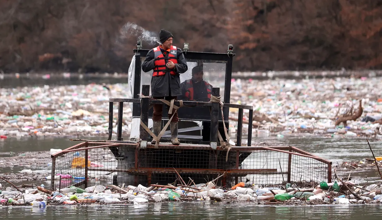 Pekerja perusahaan utilitas mendorong limbah ke tepi Sungai Lim dekat Priboj, Serbia, 30 Januari 2023. Botol plastik, papan kayu, tong berkarat, dan sampah lainnya dari tempat pembuangan sampah tepi sungai yang tidak diatur dengan baik terakumulasi selama air pasang. (AP Photo/Armin Durgut)