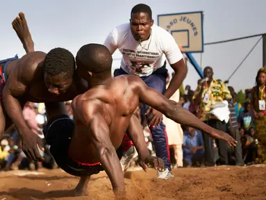 Seorang pegulat menjatuhkan lawannya dalam festival gulat tradisional di Bamako, Mali, 7 April 2019. festival gulati ini digelar setiap tahun di Bamako. (MICHELE CATTANI/AFP)