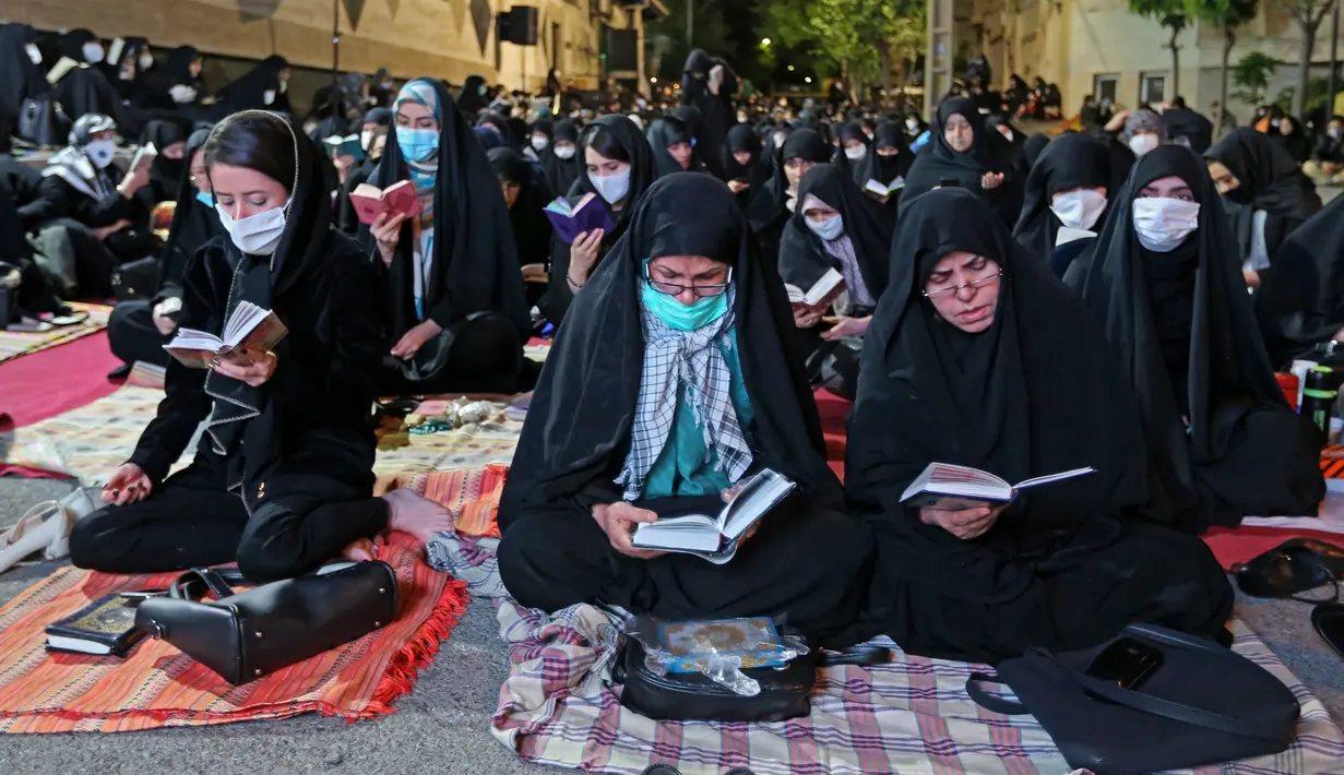 Warga Iran dengan mengenakan masker menghadiri acara kajian dan pengajian Lailatul Qadar, salah satu malam paling suci selama bulan Ramadan, di luar masjid di Teheran, Rabu (13/5/2020). Pemerintah Iran membuka kembali masjid-masjid untuk manyambut malam Lailatul Qadar. (ATTA KENARE/AFP)