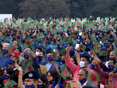 Para pejabat Bangladesh dan lainnya mengibarkan bendera nasional saat perayaan 50 tahun kemenangan atas Pakistan pada sebuah acara di Dhaka, Bangladesh, 16 Desember 2021. Pada 16 Desember 1971, tentara Pakistan menyerah kepada pasukan gabungan India-Bangladesh. (AP Photo/Mahmud Hossain Opu)