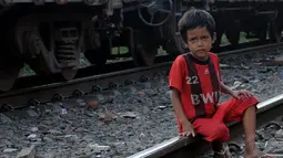 Seorang bocah laki-laki tampak duduk di bantalan rel kawasan Jakarta Barat, Jumat (20/06/14). (Liputan6.com/Faisal R Syam)