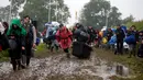 Penonton Festival Glastonbury tampak melewati jalanan yang banjir dan berlumpur saat tiba di Worthy Farm, Somerset, Inggris, (22/6). Festival Glastonbury merupakan festival musik paling populer di dunia. (REUTERS / Stoyan  Nenov)