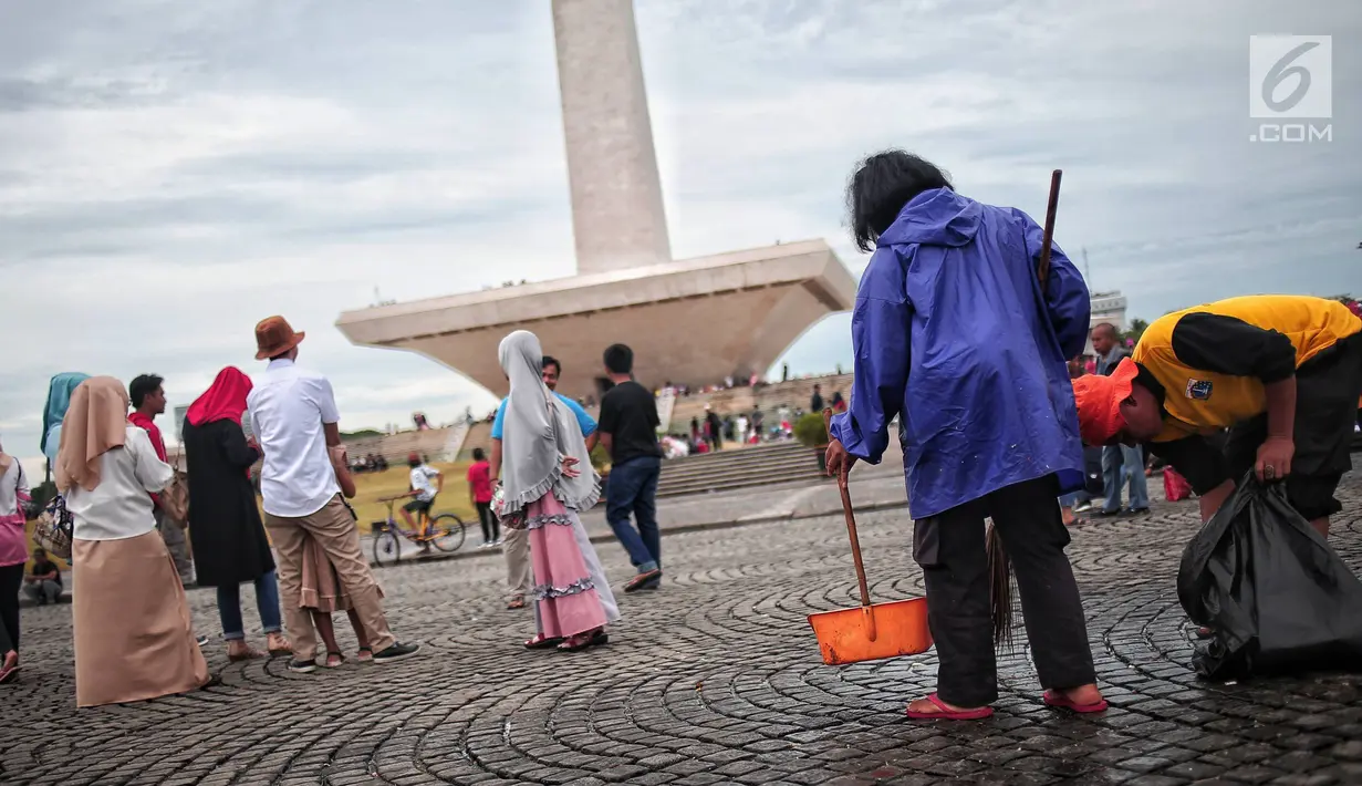 Petugas kebersihan membersihkan sisa sampah usai perayaan Tahun Baru 2019 di Monas, Jakarta, Selasa (1/1). Tak adanya pesta kembang api yang digelar oleh Pemprov DKI Jakarta disebut menjadi faktor menurunnya total sampah. (Liputan6.com/Faizal Fanani)