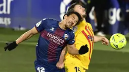 Pemain Barcelona, Clement Lenglet, duel udara dengan pemain Huesca, Shinji Okazaki, pada laga Liga Spanyol di Stadion El Alcoraz, Minggu (3/1/2021). Barcelona menang tipis dengan skor 1-0. (AP/Alvaro Barrientos)