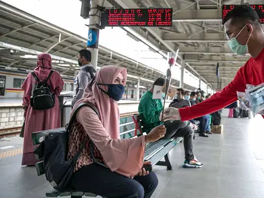 Petugas KAI Commuter (kanan) memberikan bunga dan healthy kit kepada perempuan pengguna KRL di Stasiun Jatinegara, Jakarta, Selasa (22/12/2020). Kegiatan tersebut dalam rangka memperingati Hari Ibu yang jatuh setiap tanggal 22 Desember. (Liputan6.com/Faizal Fanani)