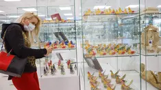 Seorang wanita yang memakai masker mengabadikan gambar pada pameran kesenian rakyat tradisional Rusia di Moskow, Rusia, 4 Oktober 2020. Lebih dari 1.000 karya seni tradisional Rusia buatan produsen kerajinan terkemuka dipamerkan di acara tersebut. (Xinhua/Alexander Zemlianichenko Jr)
