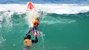 Seekor anjing berselancar bersama pemiliknya saat kompetisi tahunan City Surf Dog di Huntington Beach, California, Sabtu (29/9). Para anjing peserta yang dipandu pemilik mereka diberi kesempatan menunjukkan kebolehan berselancar. (AFP/Frederic J. BROWN)