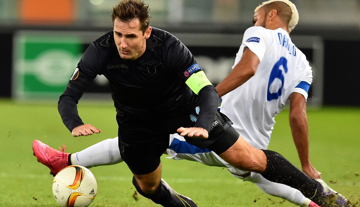 Striker Lazio, Miroslav Klose, berebut bola dengan pemain Dnipropetrovsk, Danilo, dalam lanjutan Grup G Liga Europa yang berlangsung di Stadion Olimpico, Roma, Jumat (27/11/2015) dini hari WIB. (AFP Photo/Gabriel Bouys)