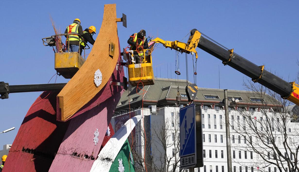 Pekerja memasang dekorasi dengan logo Olimpiade Musim Dingin di Beijing, China, Selasa (11/1/2022). Beijing dalam siaga tinggi menjelang Olimpiade Musim Dingin saat China mengunci kota ketiga di tempat lain akibat COVID-19. (AP Photo/Ng Han Guan)