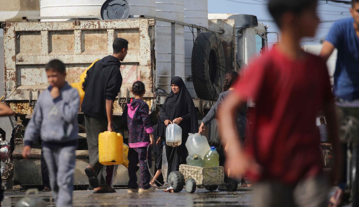 Warga Palestina mengisi wadah air di titik pengumpulan kamp pengungsi Nuseirat, yang terletak di Jalur Gaza tengah, pada 2 November 2025. Masih terdapat ribuan anak tidur dalam keadaan lapar setiap malam, meskipun telah ada kesepakatan gencatan senjata antara Israel dan Hamas di Gaza yang dimulai pada 10 Oktober 2025. (EYAD BABA/AFP)