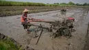 Petani membajak sawah dengan traktor sebelum menanam bibit padi di Sidoarjo, Jawa Timur, Rabu 3 Juni 2026. (JUNI KRISWANTO/AFP)