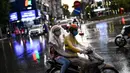 Seorang penumpang berlindung di bawah kantong plastik dengan pengemudi ojek saat hujan di Hanoi, ibu kota Vietnam pada 11 Agustus 2020. Setelah mencatat nol kasus COVID-19 selama lebih dari tiga bulan, Vietnam melaporkan sejumlah infeksi baru di dalam negeri sejak akhir Juli. (MANAN VATSYAYANA/AFP)