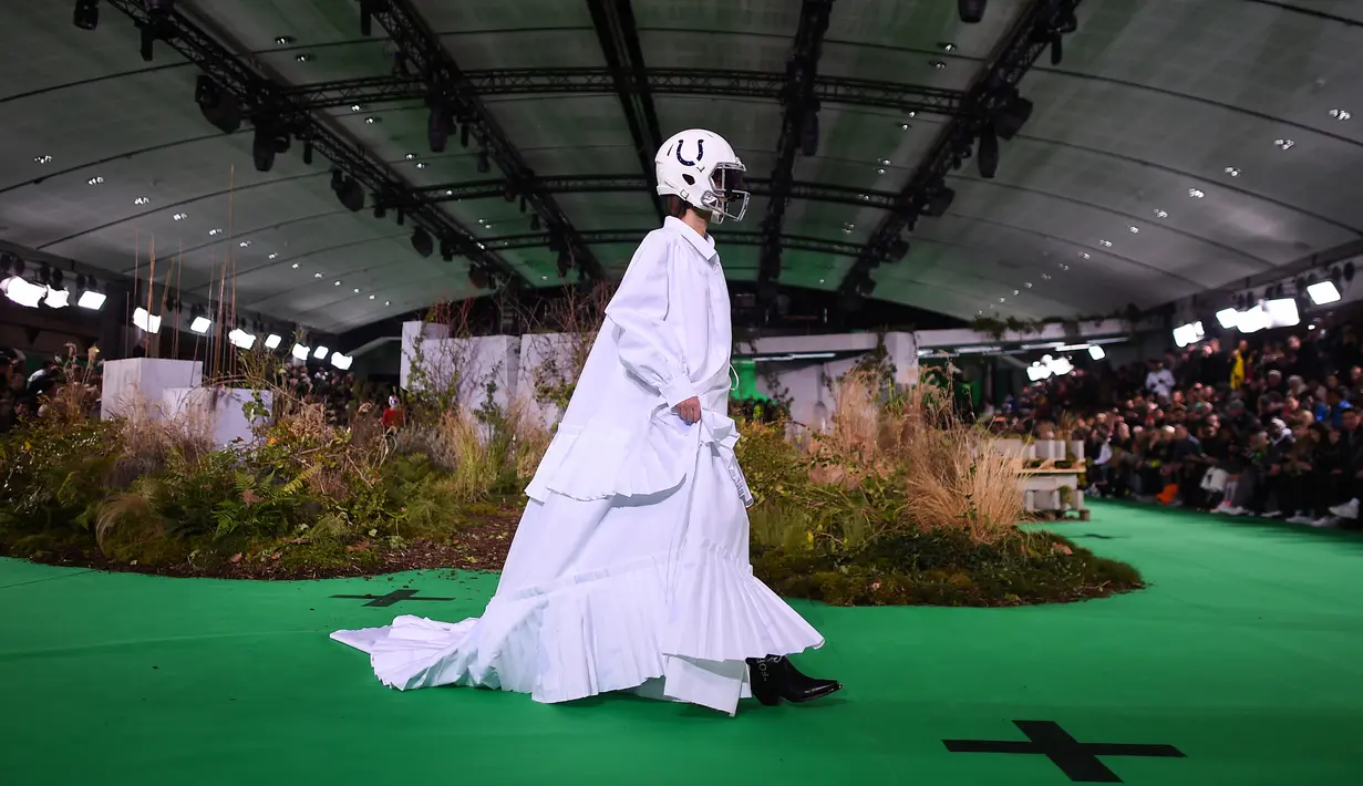 Model berjalan di atas catwalk mengenakan rancangan koleksi Fall/Winter 2019 dari brand Off-White di Paris Fashion Week, Rabu (16/1). Dalam perhelatan itu, sejumlah model mengenakan helm futbol, saat melenggang di catwalk. (Anne-Christine POUJOULAT / AFP)