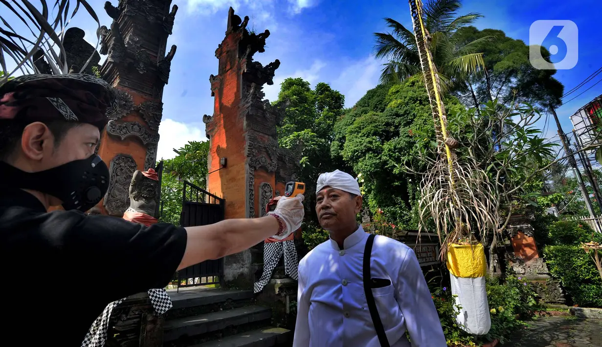 Petugas memeriksa suhu tubuh pengurus Pura Amerta Jati menjelang persiapan Hari Raya Nyepi Saka 1942 di Cinere, Depok, Selasa (24/3/2020). Rangkaian perayaan Nyepi di sejumlah pura hanya akan dilakukan oleh panitia dalam jumlah terbatas untuk mencegah penyebaran Covid-19. (merdeka.com/Arie Basuki)