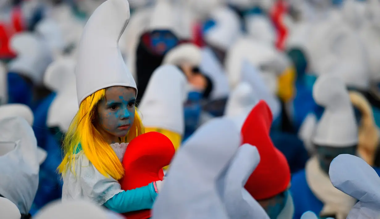Seorang anak berpakaian Smurf duduk di pundak orang dewasa selama pemecahan rekor pertemuan terbesar di dunia, di Landerneau, Prancis barat, Sabtu (7/3/2020). Acara tersebut untuk memecahkan rekor sebelumnya yang dilakukan di Jerman dengan 2.762 orang pada 2019. (Photo by Damien MEYER / AFP)