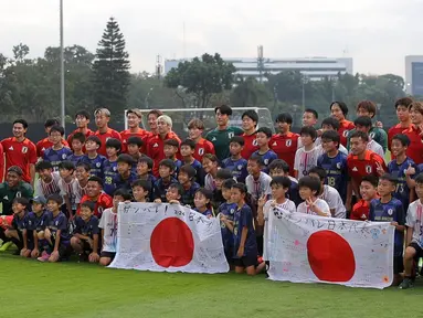 Sejumlah anak-anak yang tergabung ke dalam sekolah sepak bola Jakarta Japan Club (JJC) berfoto bersama dengan para pemain Timnas Jepang sebelum sesi latihan yang berlangsung di Lapangan A, Senayan, Jakarta, Selasa (12/11/2024). (Bola.com/Bagaskara Lazuardi)