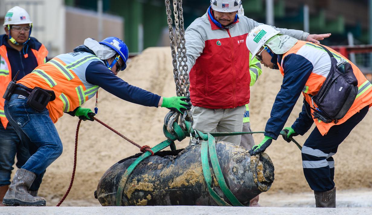 Tim penjinak bom mengangkat bom era Perang Dunia II di lokasi konstruksi di distrik padat Wan Chai, Hong Kong, Kamis (1/2). Sedikitnya 4.000 orang terpaksa dievakuasi dan sekitar lokasi ditutup selama upaya penjinakan bom. (AFP/ Anthony WALLACE)