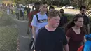 Sejumlah siswa dievakuasi ketika terjadi penembakan massal sekolah menengah Marjory Stoneman Douglas di Parkland, Florida, Rabu (14/2). Serangan ini akan menjadi salah satu tragedi penembakan paling mematikan dalam sejarah AS. (Michele Eve Sandberg/AFP)