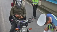 Polisi menilang pengendara sepeda motor yang menerobos jalur Transjakarta di Jalan Sultan Agung, Manggarai, Jakarta, Rabu (12/2/2020). Pengendara kerap melintasi jalur Transjakarta untuk menghindari kemacetan lalu lintas. (Liputan6.com/Herman Zakharia)