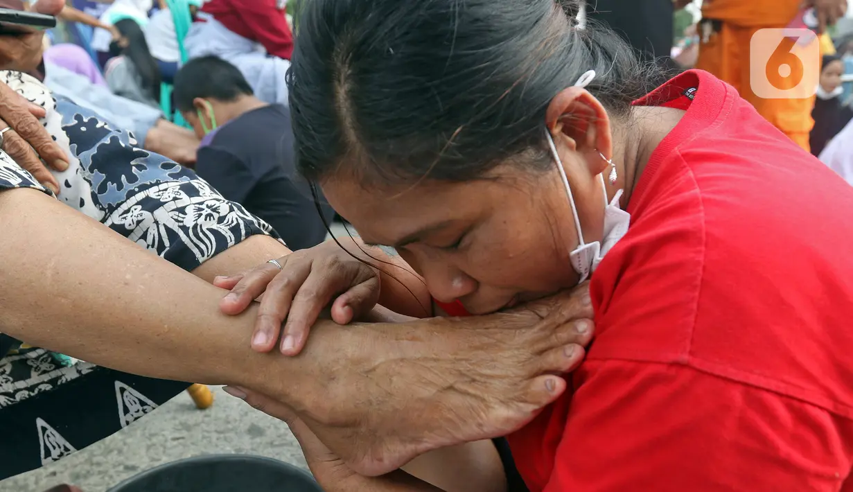 Seorang anak mencium kaki ibunya di Kelurahan Duri Pulo, Jakarta, Rabu (21/12/2021). Aksi mencuci kaki ibu secara massal yang diikuti 500 peserta itu bertujuan untuk meningkatkan rasa cinta kasih kepada ibu dan dilakukan dalam rangka memeriahkan Hari Ibu. (Liputan6.com/Herman Zakharia)