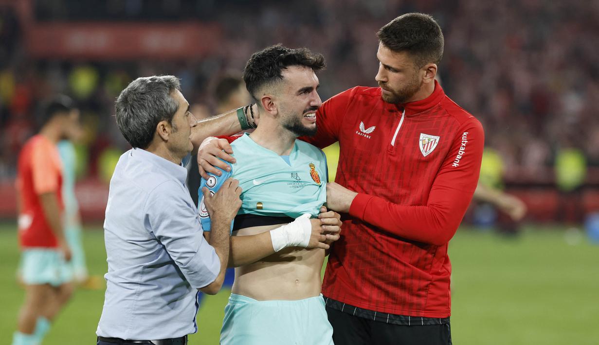 Pelatih Athletic Bilbao, Ernesto Valverde, berusaha menenangkan pemain Real Mallorca, Manuel Morlanes, setelah laga final Copa del Rey di Stadion Olimpico de Sevilla, Minggu (7/4/2024). Bilbao menang 4-2 atas Mallorca dalam drama adu penalti. (AFP/Jaime Reina)