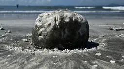 Benjolan minyak kelapa sawit terbawa hingga ke tepi sebuah pantai di Hong Kong, Senin (7/8). Sepuluh pantai di Hong Kong ditutup pada Minggu (6/8) setelah minyak sawit tumpah akibat tabrakan kapal di perairan China. (Anthony WALLACE / AFP)