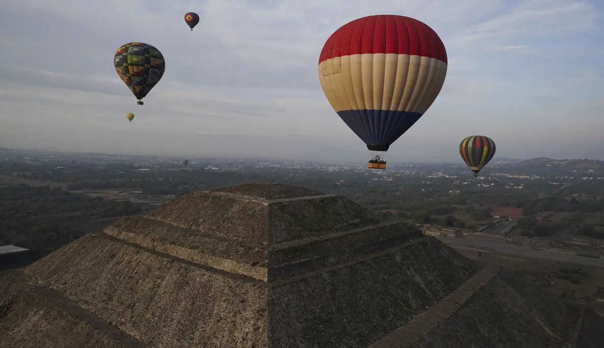 Balon udara yang dipenuhi turis terbang di atas piramida Matahari di situs arkeologi Teotihuacan, tepat di utara Mexico City, Minggu, 24 Desember 2023. (AP Photo/Marco Ugarte)