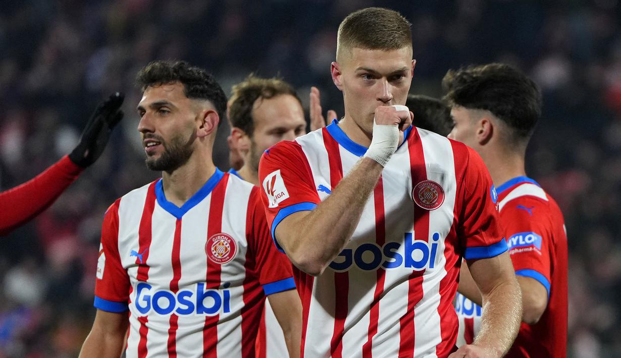 Tim penuh kejutan musim ini, Girona sukses melengserkan Real Madrid dari puncak klasemen sementara Liga Spanyol 2023/2024 setelah meraih kemenangan telak 3-0 atas Alaves pada laga pekan ke-17 di Montilivi Stadium, Girona, Selasa (19/12/2023) dini hari WIB. Mengoleksi 44 poin, Girona unggul dua poin atas Real Madrid. Bintang kemenangan Girona dalam laga tersebut tak lain adalah striker asal Ukraina, Artem Dovbyk yang sukses mencetak brace. (AFP/Pau Barrena)