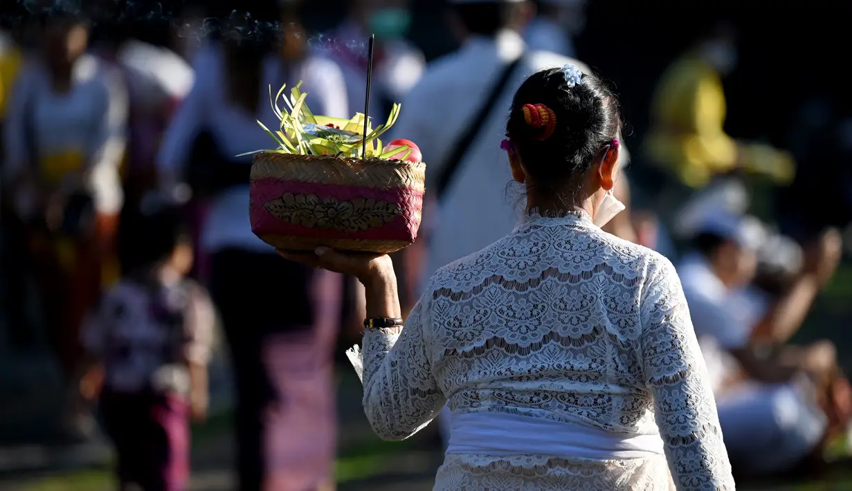 Seorang perempuan umat Hindu membawa sesajen untuk perayaan hari raya Galungan di Pura Jagat Natha di Denpasar, Bali, Rabu (8/6/2022). Di tahun 2022 ini, Hari Raya Galungan jatuh pada tanggal 8 Juni dan diikuti Hari Raya Kuningan pada tanggal 18 Juni. (SONNY TUMBELAKA / AFP)