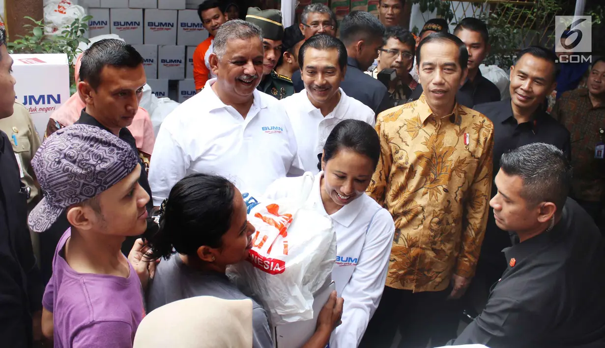 Menteri BUMN Rini Soemarno disaksikan Presiden Jokowi membagikan paket Ramadan berupa sembako kepada warga di wilayah Penjaringan, Jakarta, Selasa (13/6). Sebanyak 14 perusahaan BUMN turut serta dalam pembagian sembako ini. (Liputan6.com/Angga Yuniar)