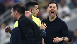 Xabi Alonso berusaha meredam aksi panas tersebut. Ia mencoba menahan dan menenangkan pemainnya, Vinicius Jr. (AFP/Fadel Senna)