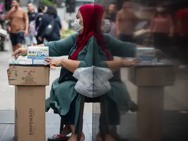 Seorang wanita menjual masker di tengah kekhawatiran akan penyebaran virus corona COVID-19, di Kuala Lumpur, Malaysia, Kamis, (13/2/2020). WHO kini tidak lagi menyebut virus yang merebak di China sebagai Virus Corona Baru. (AFP/Mohd Rasfan)