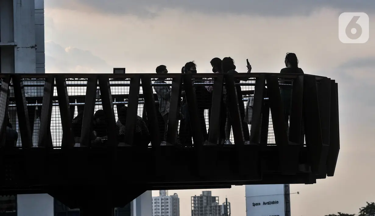 Warga berfoto saat ngabuburit di JPO Pinisi Pinisi Karet-Sudirman, Jakarta Pusat, Senin (4/4/2022). JPO Pinisi kini menjadi destinasi baru warga Jakarta untuk menunggu waktu berbuka puasa atau ngabuburit sambil menikmati suasana perkotaan. (merdeka.com/Iqbal S. Nugroho)
